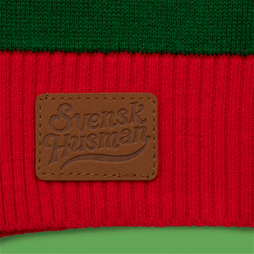 Brown leather Svenskhusman logo patch on a red and green knitted Alfons Åberg Christmas sweater.
