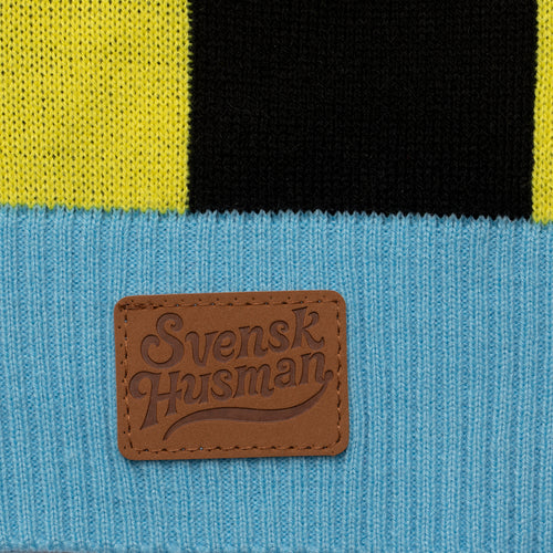 Detalj av jultröja Tomte Sån där färg med Svenskhusman-logotyp på stickat tyg.