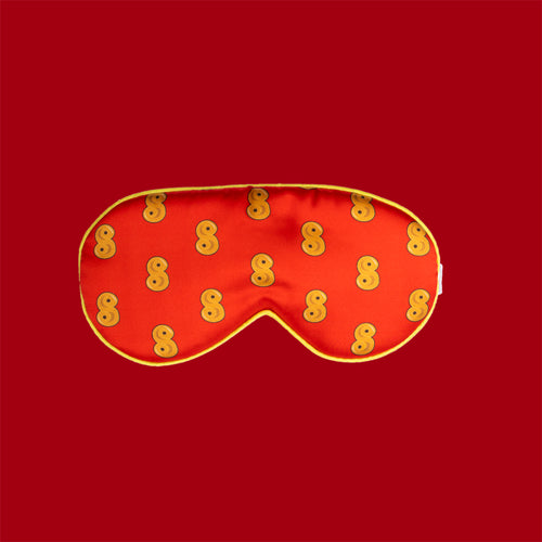 Röd sovmask i mjuk polyester med mönster av gula lussebullar från Svenskhusman.