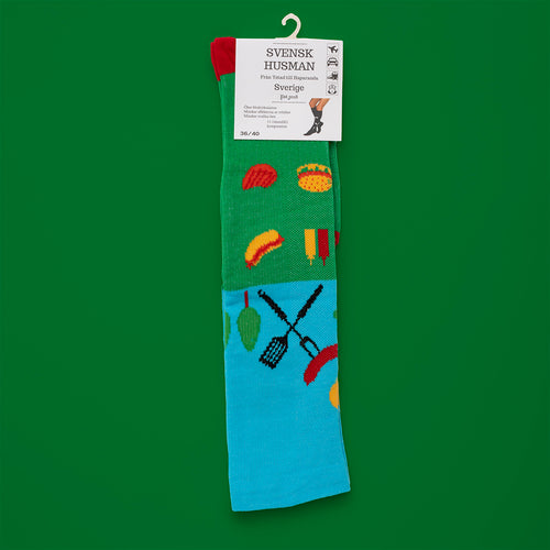 Grüne und blaue Stützstrümpfe mit Grill- und Wurstmotiven von Svenskhusman auf grünem Hintergrund.
