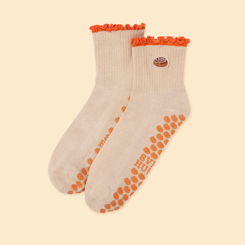 Beige pilatesstrumpor med halkskydd och kanelbulle-motiv med orange vågig kant från Svenskhusman.