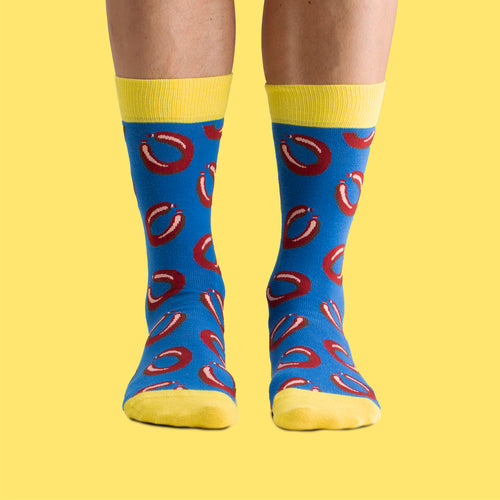 Blue and yellow socks with a falukorv sausage pattern and yellow details from Svenskhusman on a yellow background.