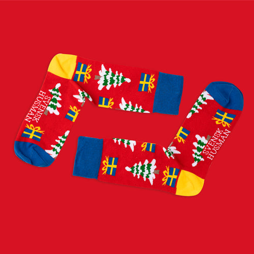 Röda julstrumpor med mönster av granar och paket i svenska flaggans färger från Svenskhusman.
