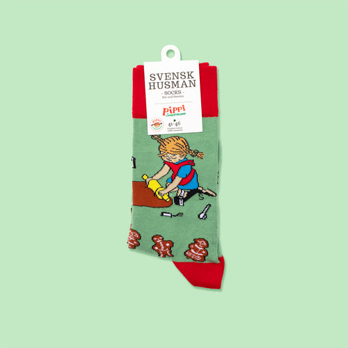 Gröna och röda Pippi Långstrump-strumpor med motiv av Pippi som bakar pepparkakor från Svenskhusman.