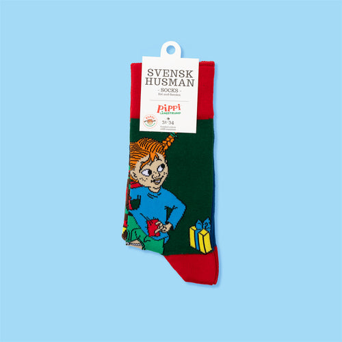 Gröna och röda julstrumpor i bomull med motiv av Pippi Långstrump som räddar julen från Svenskhusman.