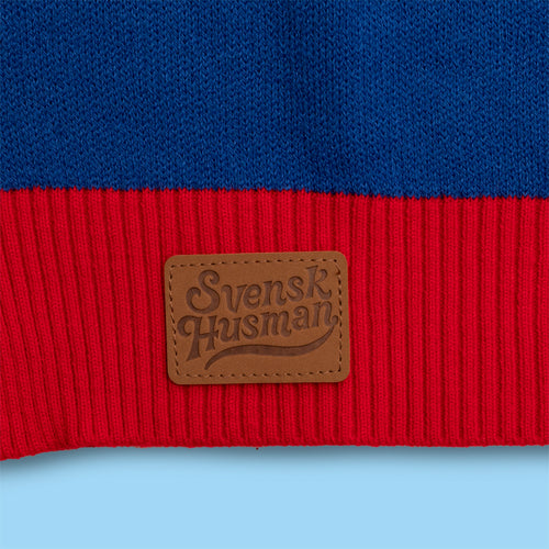 Knitted blue and red Christmas sweater featuring a brown leather Svenskhusman patch.