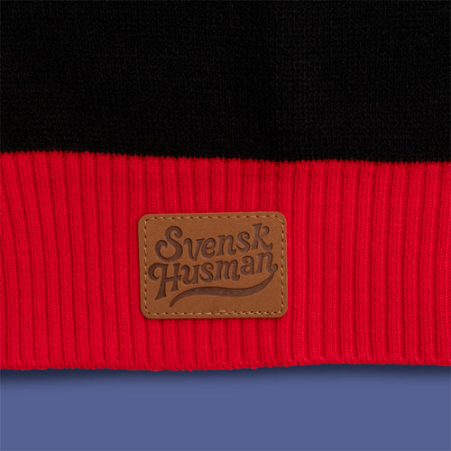 Black and red knitted Christmas sweater featuring a brown faux leather Svenskhusman logo patch.