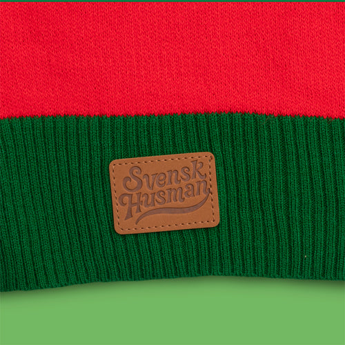 Stickad röd jultröja Högtid & tradition med grön mudd och Svenskhusmans logotyp i läder.
