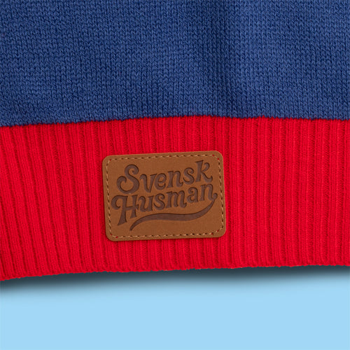 Blau-roter Lucia Weihnachtspullover mit dem Svenskhusman-Logo auf einem braunen Leder-Patch.