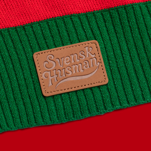 Braunes Lederetikett mit Svenskhusman-Logo auf einem grün-rot gestrickten Weihnachtspullover.