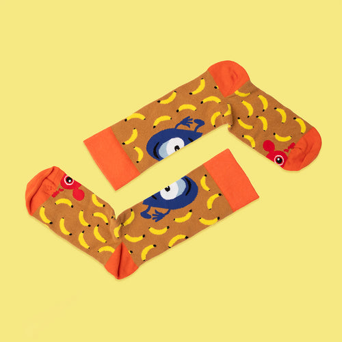 Bruna Babblarna-strumpor med orangea detaljer mönstrade med gula bananer, Doddo och Diddi.