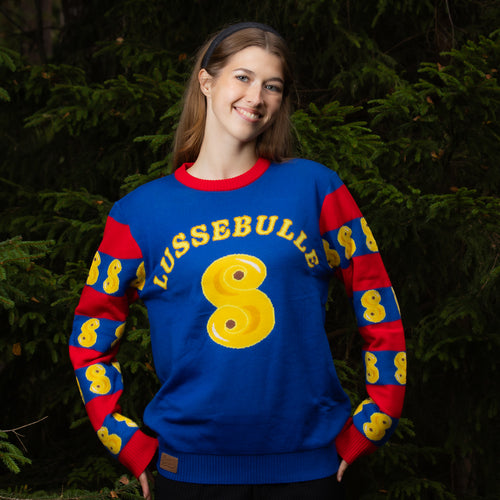 Blauer Weihnachtspullover mit Lussebulle-Motiv und roten Streifen an lächelnder Frau im Wald von Svenskhusman.