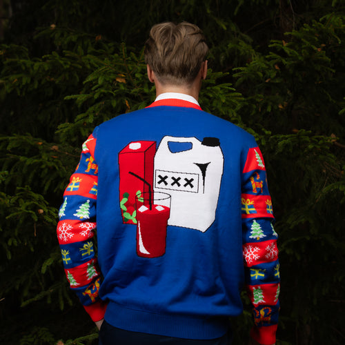 Blue Christmas sweater with a grogg motif on the back, shown in a green forest setting by Svenskhusman.