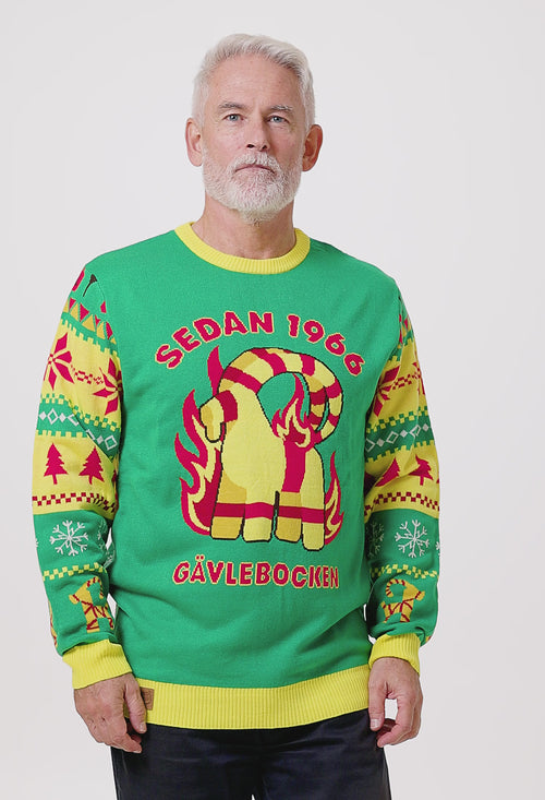 Grön stickad jultröja för herr med Gävlebocken, julgranar och snöflingor på en modell från Svenskhusman.