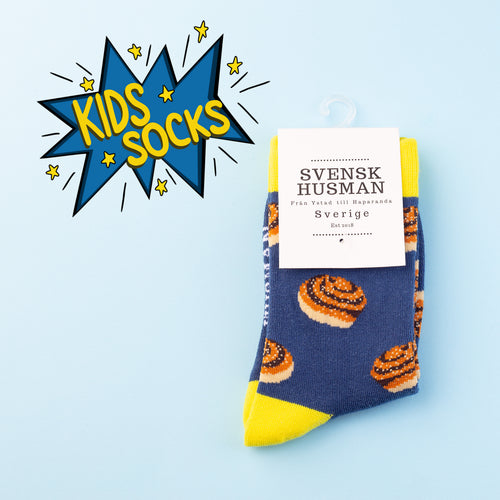 Blå barnstrumpor med motiv av kanelbullar och gula detaljer från Svenskhusman.
