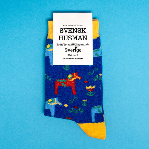 Blå barnstrumpor med motiv av röda dalahästar och gula detaljer från Svenskhusman.