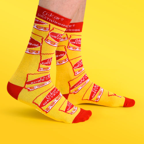 Gula strumpor med mönster av Oskars surströmmingsburkar och röda detaljer, Svenskhusman.