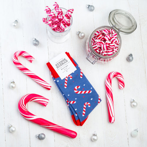Blaue Weihnachtssocken mit Zuckerstangen-Muster zwischen echten Süßigkeiten und Dekoration – Svenskhusman